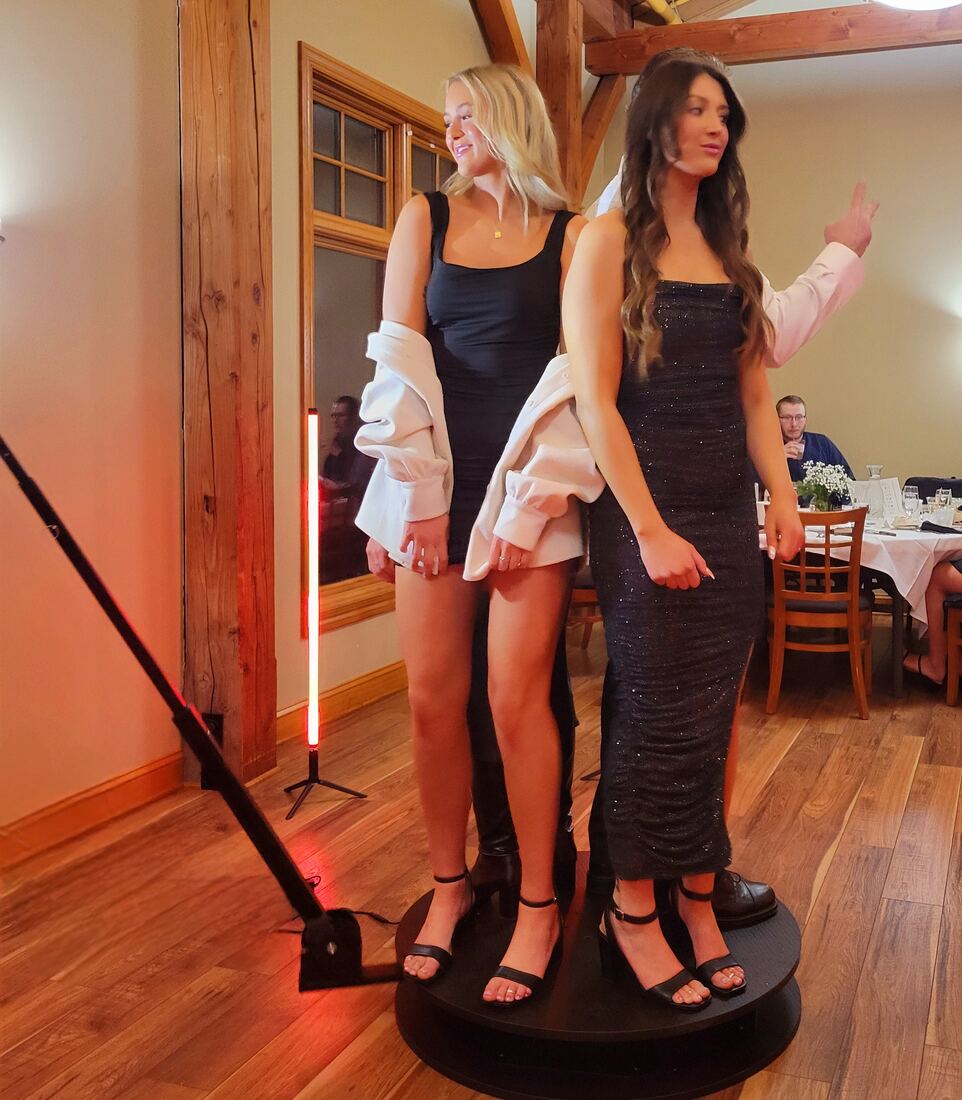 Two guests posing on the 360 photo booth platform at a wedding